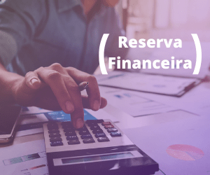 Mão com caneta fazendo um cálculo na calculadora e vários papéis e planilhas na mesa. Escrito "Reserva Financeira".