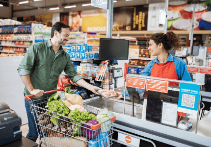 Caixa de Supermercado atendendo um homem sorridente prestes a pagar as contas.