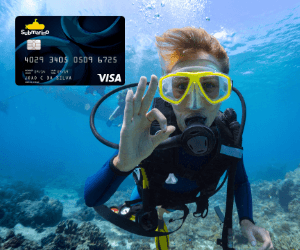 Mergulhador em alto mar, fazendo sinal de ok com a mão para o cartão de crédito Submarino que está no canto superior esquerdo.