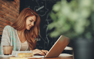 Mulher em um café usando computador para atualizar currículo.