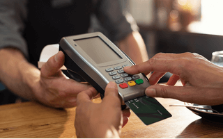 Pessoa pagando com o seu cartão de crédito em loja ou restaurante.