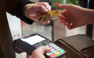 Pessoa em loja entregando seu cartão de crédito visa gold para atendente passar na maquininha
