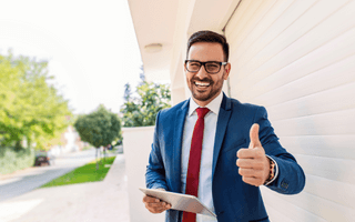 Homem sorrindo com tablet na mão fazendo sinal de positivo.