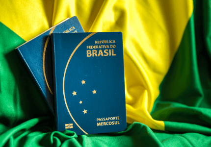 Dois passaportes brasileiros em cima da bandeira do Brasil.