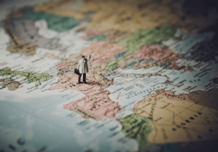 Homem miniatura em cima do mapa-múndi.