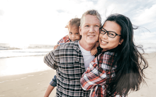 Pai, mãe e filho felizes na orla de uma praia.