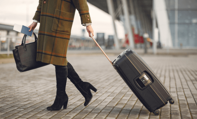 Mulher levando sua mala e bolsa com passaporte na mão.