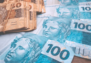 Várias notas de cem reais e de cinquenta reais sobre uma mesa.