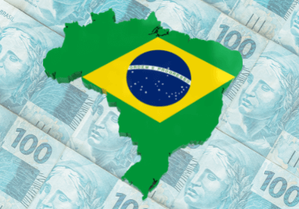 Mapa do Brasil verde e o losango amarelo da bandeira no centro. Ao fundo várias notas de cem reais que representam a volta do Brasil para o ranking com as 10 maiores economias do mundo.