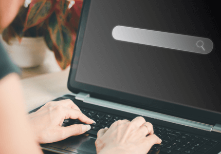 Mãos de uma pessoa digitando no teclado de um laptop fazendo uma consulta do score de crédito.