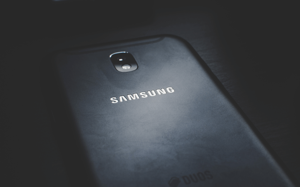 Smartphone Samsung virado com tela para baixo , num fundo preto.