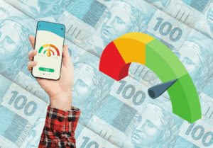 Mão segurando um celular para cima onde na tela está a escala de score de crédito. Ao lado outra escala meia lua do score de crédito e ao fundo várias notas de cem reais.