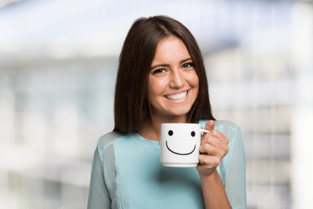 Mulher feliz segurando uma caneca de café, com um sorriso estampado 