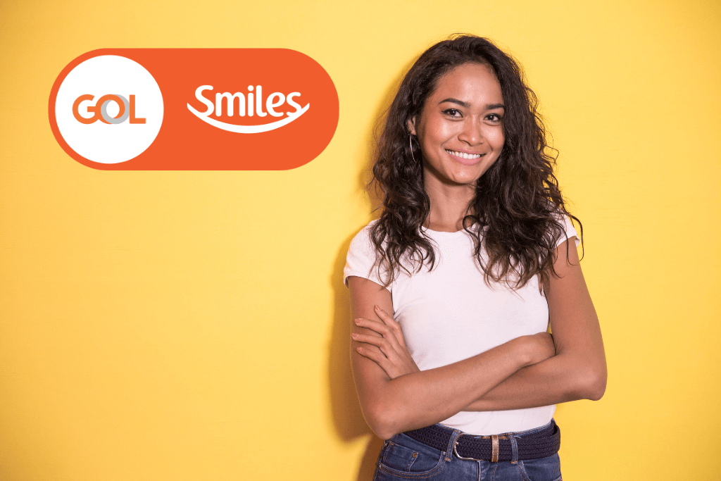 Mulher sorrindo, feliz por ter acumulado milhas graças á parceria entre a Uber e Smiles, ao lado da logo do Smiles.
