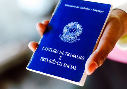 Carteira Nacional de Trabalho e Previdência Social na mão de uma pessoa.