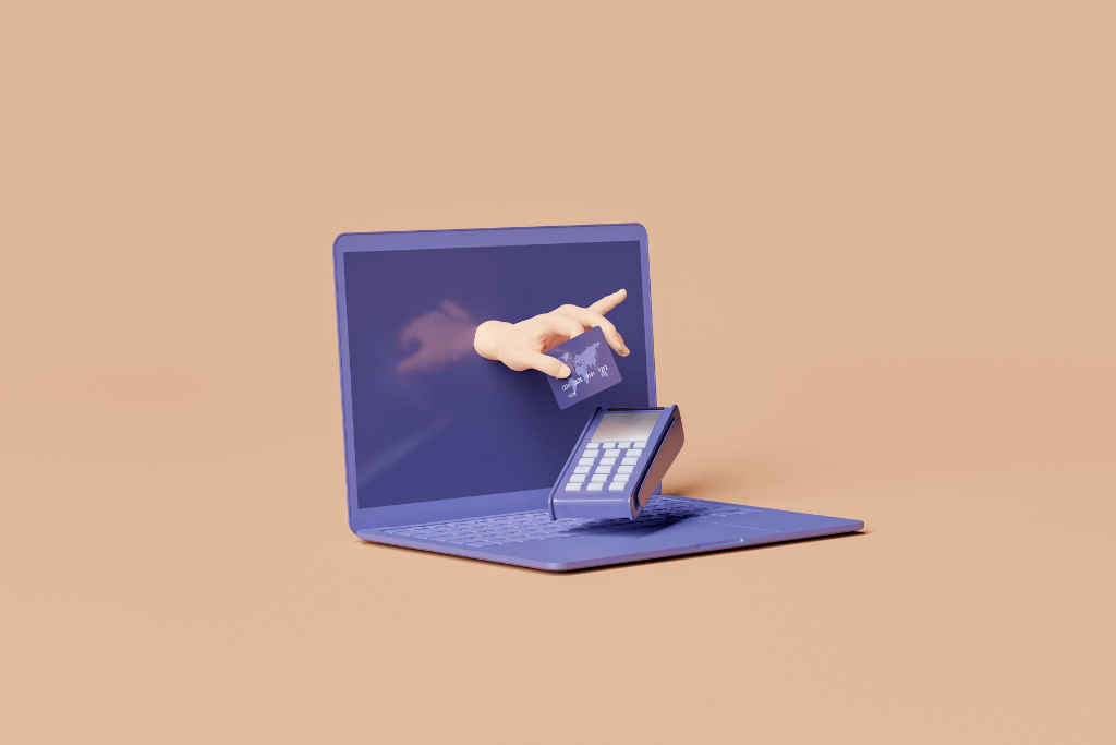 Mão segurando um cartão de crédito saindo de dentro de uma tela de computador em direção a uma maquininha de cartão, simbolizando uma compra online.