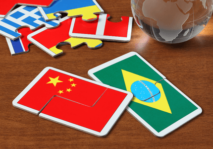 Cartões com imagens das bandeiras do Brasil, da China e de outros países em cima de uma mesa.