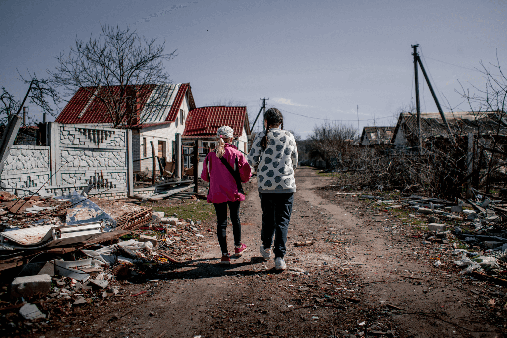 Guerra da Ucrânia, com duas pessoas andando num cenário devastado.