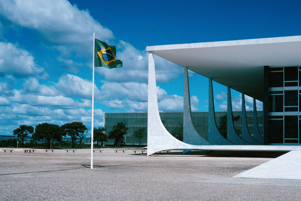 Bandeira do Brasil num mastro, ao lado de uma instalação governamental.