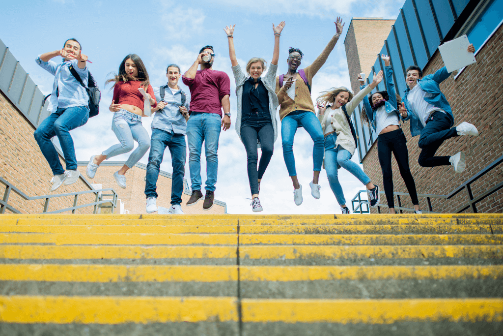 Estudantes universitários felizes na parte de cima de uma escada.