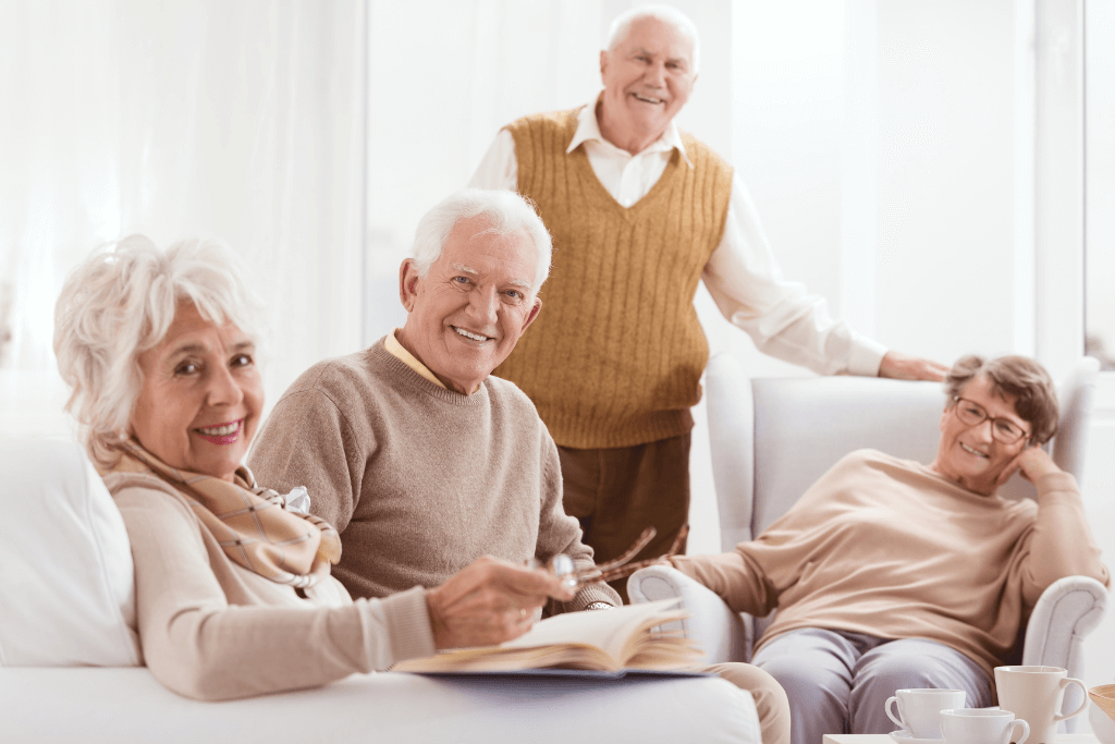 Grupo de idosos numa sala de estar, sorrindo.