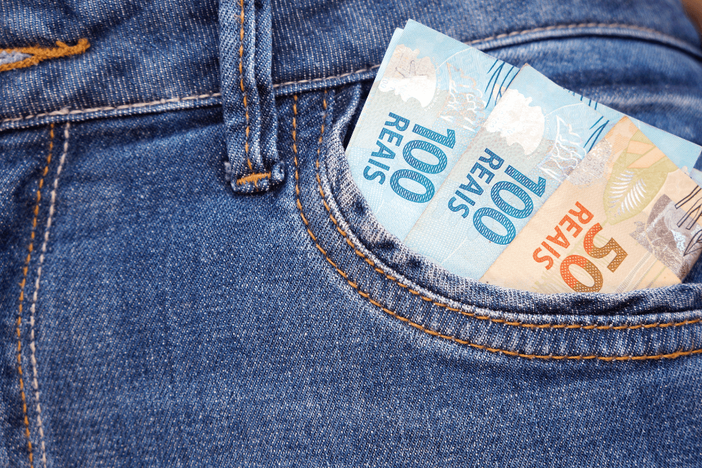 Pessoa com notas de 100, 200 e 50 reais no bolso da calça.