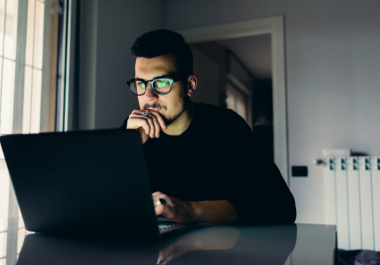 Homem usando o laptop para solicitar o cartão de crédito Bradesco Visa Infinite.