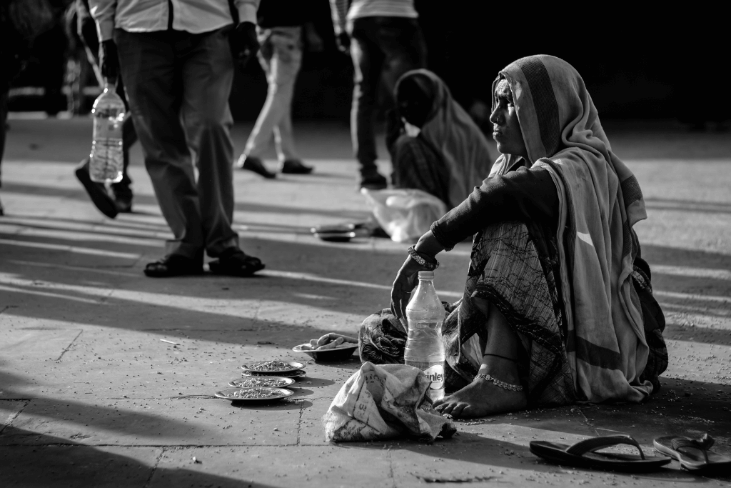 Mulher sentada na rua, pedindo esmolas.