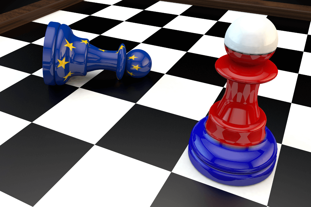Tabuleiro de xadre com dois peões estampados com as bandeiras da Rússia e da União Europeia.