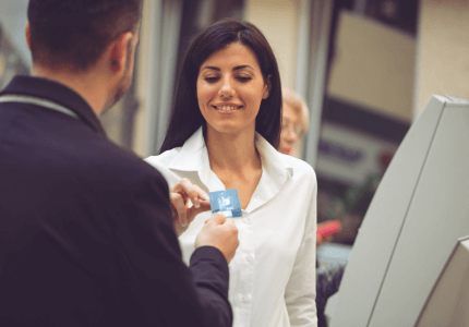 Mulher recebendo cartão de crédito emprestado, em frente ao caixa eletrônico.