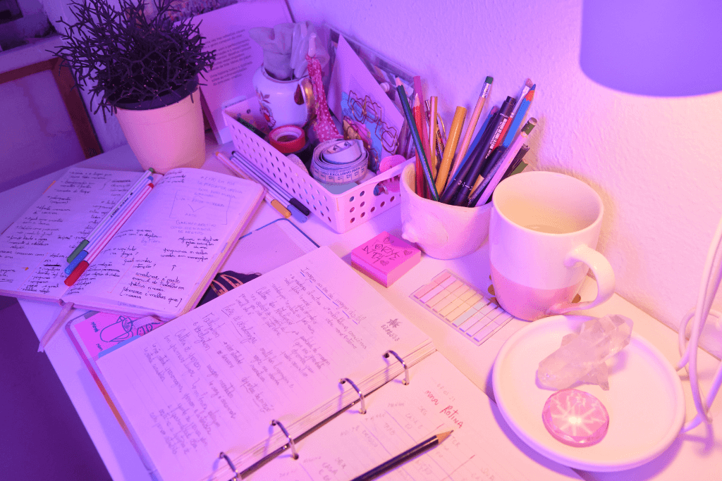 Mesa de estudos com cadernos, canetas, lápis e outros artigos de papelaria.