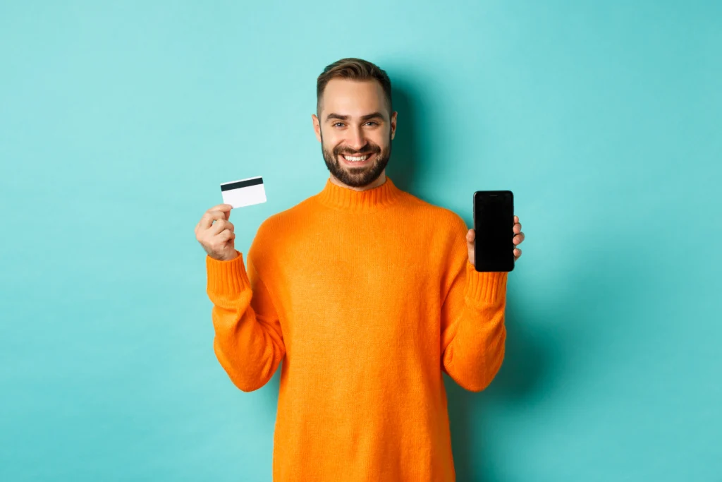 Homem sorridente segurando cartão e um celular para solicitar Gol Smiles