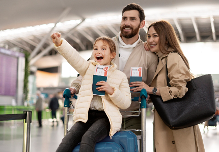 Familia lista para viajar en el aeropuerto con valijas y pasaportes, representando beneficios y ahorro con tarjetas para viajar.