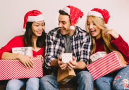 Personas intercambiando regalos de Navidad y celebrando con cajas de regalos, ideal para compras navideñas con tarjetas de crédito y promociones en cuotas sin interés.