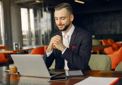 Empresario trabajando en laptop en una oficina moderna mientras analiza tarjetas para PYMES y la gestión financiera del negocio.