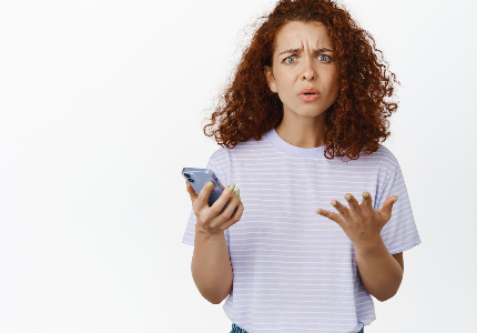 Mulher com expressão de preocupação segurando celular molhado, representando dano por líquido e acionamento de seguro de celular