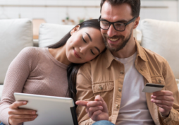 Casal analisando compras no tablet enquanto segura cartão de crédito, representando uso de cartão adicional e controle de gastos familiares