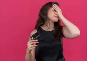 mujer preocupada sosteniendo tarjeta de crédito con expresión de frustración, concepto de tarjeta bloqueada y problemas financieros